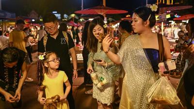 This photo taken on July 20, 2021 shows people looking at wooden elephant figures for sale at a night market in Jinghong in southwest China's Yunnan province. (AFP/File) This photo taken on July 20, 2021 shows people looking at wooden elephant figures for sale at a night market in Jinghong in southwest China's Yunnan province. (AFP/File)