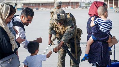 A US Marine assigned to 24th Marine Expeditionary Unit fists bumps a child evacuee during an evacuation at Hamid Karzai International Airport, Kabul, Afghanistan. (REUTERS)