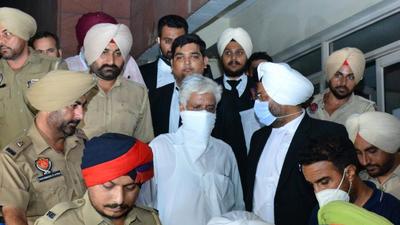 Punjab Police former chief Sumedh Singh Saini (centre) being escorted out of the Mohali chief judicial magistrate’s court around 2am on Friday. (Keshav Singh/HT) Punjab Police former chief Sumedh Singh Saini (centre) being escorted out of the Mohali chief judicial magistrate’s court around 2am on Friday. (Keshav Singh/HT)