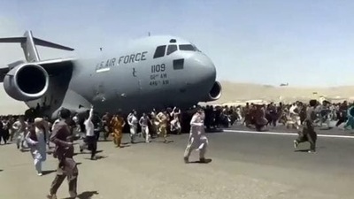 Hundreds of people run alongside a US Air Force C-17 transport plane as it moves down a runway of the international airport, in Kabul, Afghanistan. (AP) Hundreds of people run alongside a US Air Force C-17 transport plane as it moves down a runway of the international airport, in Kabul, Afghanistan. (AP)