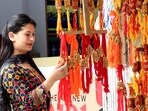 A woman looks at the rakhis hanged to buy ahead of the Raksha Bandhan festival, in Kullu on Saturday.(ANI Photo)