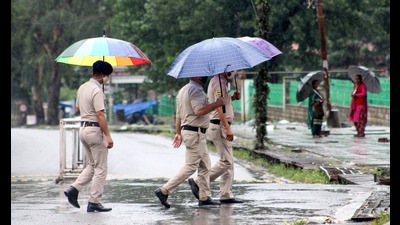 Police personnel carrying umbrellas amid rain in Kullu on Saturday. (Aqil Khan/HT)