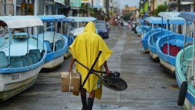 A man carries a fan and a box while walking past tourist boats that were moved from the water for safety as Hurricane Grace gathered more strength before reaching land, in Tecolutla, Mexico. (REUTERS)