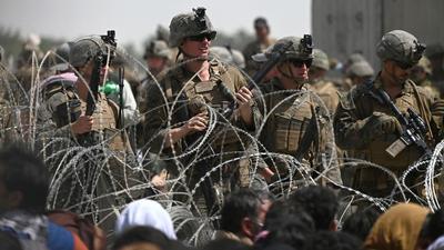 US soldiers stand guard behind barbed wire as Afghans sit on a roadside near the military part of the airport in Kabul on August 20, 2021, hoping to flee from the country after the Taliban's military takeover of Afghanistan (AFP) US soldiers stand guard behind barbed wire as Afghans sit on a roadside near the military part of the airport in Kabul on August 20, 2021, hoping to flee from the country after the Taliban's military takeover of Afghanistan (AFP)