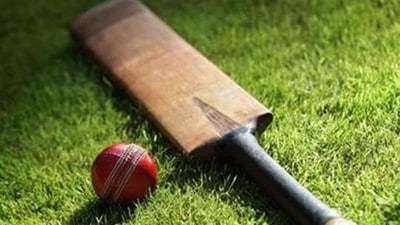 Cricket bat and ball on green grass of cricket pitch Cricket bat and ball on green grass of cricket pitch