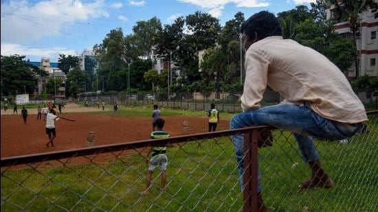 A boy waits for his turn to bat as others play cricket on Jeet ground in Pune. (Sanket Wankhade/HT PHOTO)
