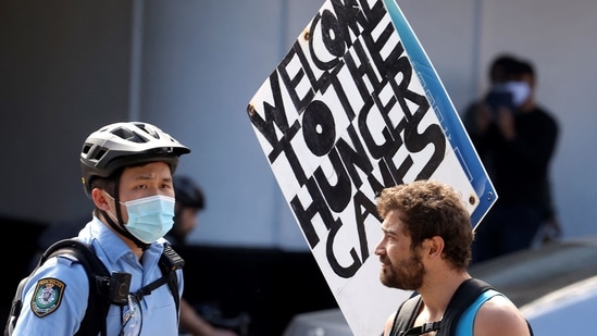 A police officer stops a protestor with placards in Sydney on August 21, 2021, following calls for an anti-lockdown protest rally amid a fast-spreading Covid outbreak. (AFP) A police officer stops a protestor with placards in Sydney on August 21, 2021, following calls for an anti-lockdown protest rally amid a fast-spreading Covid outbreak. (AFP)