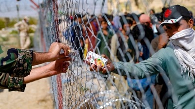 A handout picture made available by the Iranian Red Crescent shows a soldier distributing boxes of juice to Afghan refugees gathered at the Iran-Afghanistan border between Afghanistan and the southeastern Iranian Sistan and Baluchestan province, as they try to enter the Islamic republic following the takeover of their country by the Taliban last week. (AFP) A handout picture made available by the Iranian Red Crescent shows a soldier distributing boxes of juice to Afghan refugees gathered at the Iran-Afghanistan border between Afghanistan and the southeastern Iranian Sistan and Baluchestan province, as they try to enter the Islamic republic following the takeover of their country by the Taliban last week. (AFP)