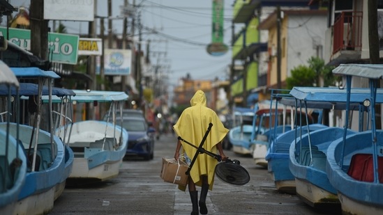 A resident carries a box and fan on an empty street after Hurricane Grace made landfall in Tecolitla, Veracruz state in Mexico on Saturday, August 21.(Bloomberg)