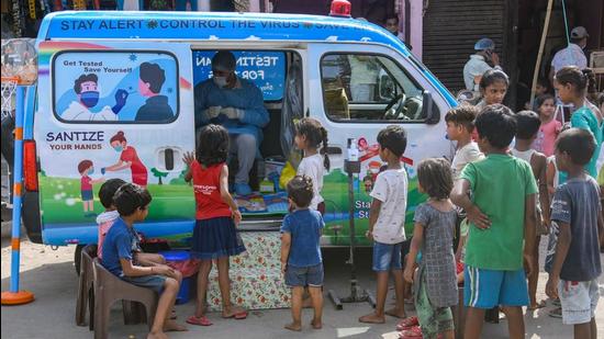 Underprivileged children wait outside a van decorated with toys for their Covid-19 test in New Delhi. (ANI PHOTO.)