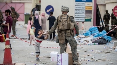 A US Marine provides a meal ready-to-eat to a child during an evacuation at Hamid Karzai International Airport, Kabul, Afghanistan, (via REUTERS)