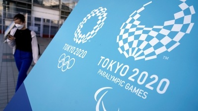 A woman walks near a sing of the Tokyo 2020 Olympic and Paralympic Games, Friday, Aug. 20, 2021, in Tokyo. (AP)