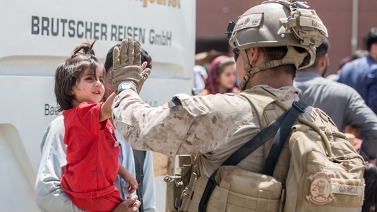 A US Marine receives a high-five from a child during an evacuation at Hamid Karzai International Airport, Kabul, Afghanistan, (via REUTERS)