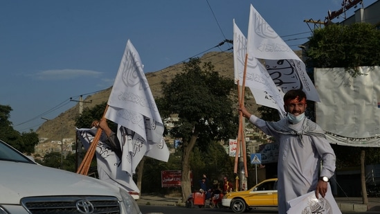 People carry Taliban flags to sell at the Karte Mamorin area of Kabul city. (Photo by Hoshang Hashimi / AFP)(AFP)