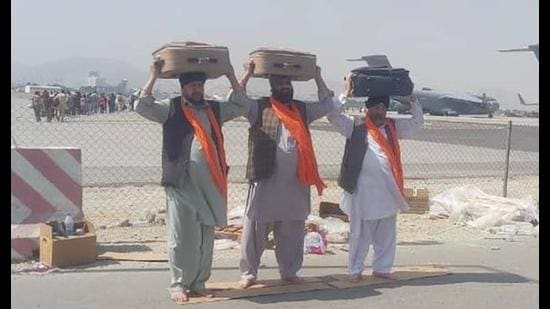 Three Afghan Sikhs carrying the Guru Granth Sahib from different gurdwaras in Afghanistan at the Kabul airport before their departure to India. (PTI)