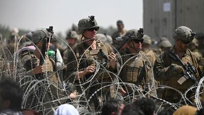 US soldiers stand guard behind barbed wire as Afghans sit on a roadside near the military part of the airport in Kabul on August 20, hoping to flee from the country after the Taliban's military takeover of Afghanistan. (File photo) US soldiers stand guard behind barbed wire as Afghans sit on a roadside near the military part of the airport in Kabul on August 20, hoping to flee from the country after the Taliban's military takeover of Afghanistan. (File photo)