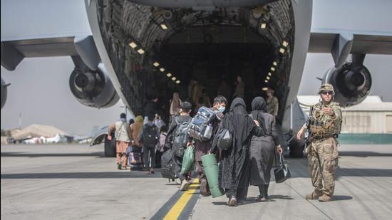 Families begin to board a US Air Force Boeing C-17 Globemaster III aircraft during an evacuation operation at Hamid Karzai International Airport in Kabul, Afghanistan on August 23, 2021. (AFP)