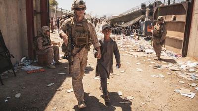 A US Marine escorts a child to his family during an evacuation at Hamid Karzai International Airport in Kabul, Afghanistan, on Tuesday. (REUTERS)
