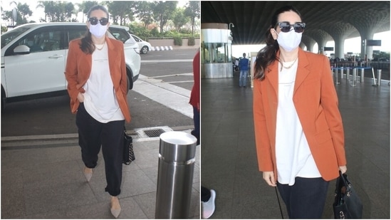 Karisma carried a black top handle bag with her boss lady attire. She completed her airport look with grey suede shoes, sunglasses, a chunky gold chain, and a face mask. She tied her locks in a sleek ponytail and kept her make-up minimal.(HT Photo/Varinder Chawla)