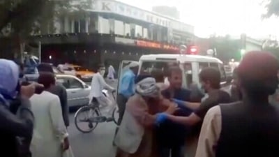 In this image taken from video, people tend to a wounded person near the site of a deadly explosion outside the airport in Kabul, Afghanistan, (AP) In this image taken from video, people tend to a wounded person near the site of a deadly explosion outside the airport in Kabul, Afghanistan, (AP)