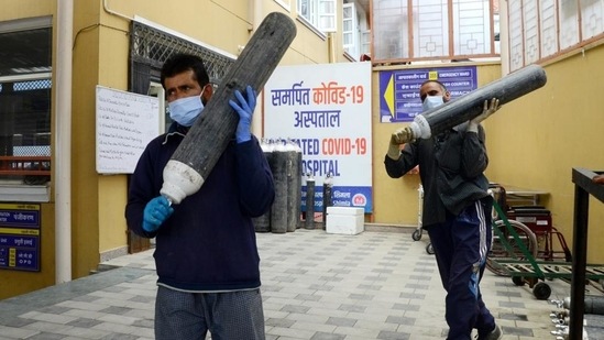 The need for medical oxygen to treat Covid-19 infections ballooned severely during the second wave of infections. In picture - Health workers carrying oxygen cylinders.(HT File Photo)