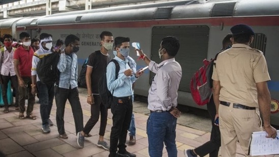 A healthcare worker checks temperatures before Covid-19 test of passengers arriving from outstation trains at Dadar station. (Pratik Chorge/HT PHOTO)