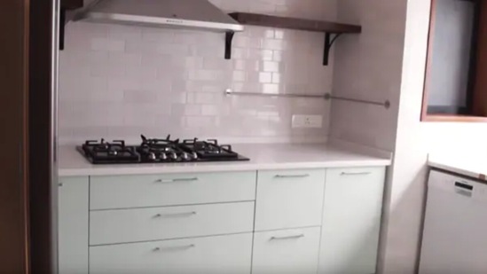 Alia's kitchen comes fitted with white tiles and mint green cupboards.