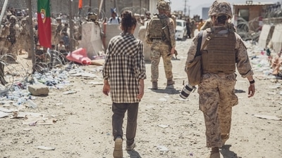 The US Marine Corps, a Marine with Special Purpose Marine Air-Ground Task Force - Crisis Response - Central Command, escorts a young girl at an evacuation control checkpoint during an evacuation at Hamid Karzai International Airport in Kabul, Afghanistan, (AP)