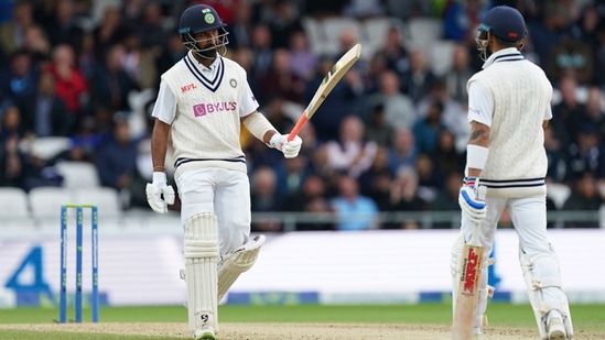 Cheteshwar Pujara, left, raises his bat to celebrate scoring fifty runs during the third day of third Test(AP)