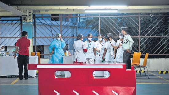Health workers converse during a drive in facility for Covid-19 vaccination at a car parking area of a shopping mall in Kochi on Friday. (AP)