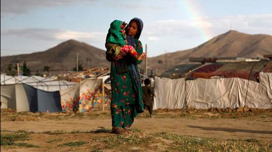 An internally displaced Afghan girl carries a child near their shelter at a camp on the outskirts of Kabul, Afghanistan. (REUTERS File)