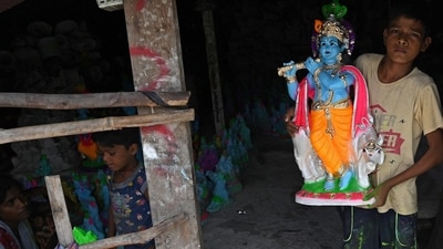 A boy carries an idol of Lord Krishna to put on display for sale ahead of 'Janmashtami' at a workshop along the roadside in Chennai. (AFP)