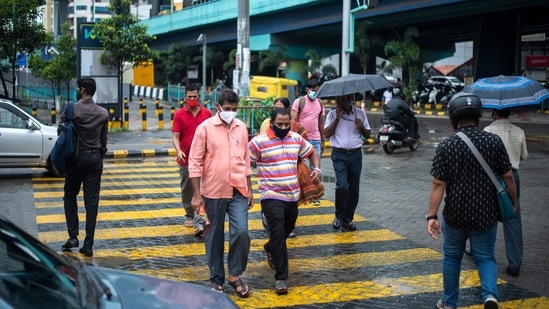 People wearing face masks as a precaution against Covid-19 walk at a pedestrian crossing in Kochi.(AP Photo)