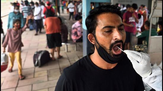 A BMC health worker collects swab sample of a passengers at Dadar station in Mumbai on Sunday. (Satish Bate/HT Photo)