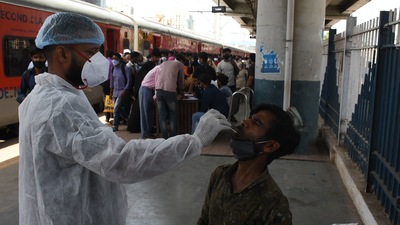 A BMC health worker collects swab samples for Covid-19 test of commuters arriving from outstation trains at Dadar station, in Mumbai. (Bhushan Koyande/ HT Photo)