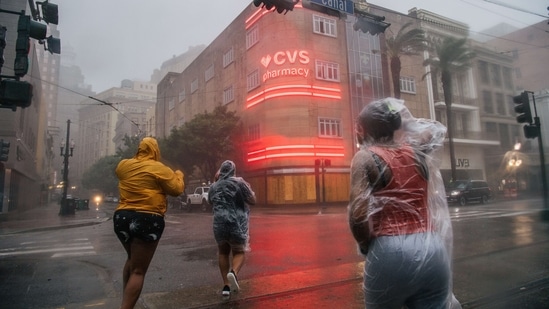A group of people cross an intersection during Hurricane Ida in New Orleans, Louisiana on August 29. The levees, pumps and other infrastructure rebuilt after Hurricane Katrina in 2005 storm are being put to their biggest test yet. Louisiana’s hospitals are already overwhelmed with more than 2,600 coronavirus patients, Bloomberg reported.(Brandon Bell / AFP)