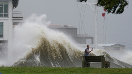 A man takes pictures of high waves along the shore of Lake Pontchartrain in New Orleans on August 29. More than 1 million homes and businesses in Louisiana and about 100,000 in Mississippi were without power on August 29, according to Poweroutage.us.(Gerald Herbert / AP)