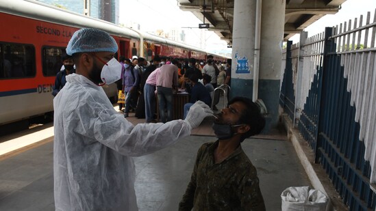 A BMC health worker collects swab samples for Covid-19 test of commuters arriving from outstation trains at Dadar station, in Mumbai. (Bhushan Koyande/ HT Photo)
