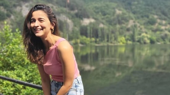 She appears to be nears a lake with lush greenery all around her.