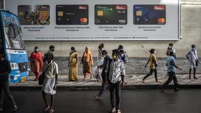 People wearing masks as a precaution against Covid-19 wait to board buses as others walk in Kochi, Kerala. (AP File)