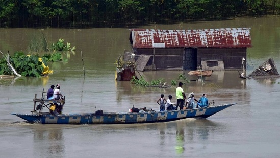 Locals use a boat to move across a flooded locality, in Morigaon.(ANI)