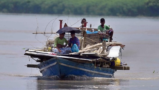 Locals transport their belongings through a boat at a flooded village, in Morigaon.(ANI)