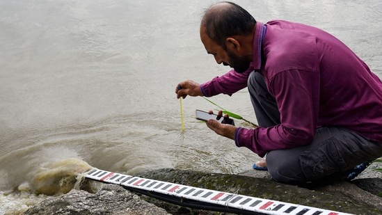 An employee of Central Water Commission (CWC) measures the temperature of the Brahmaputra river's water, which is flowing above the danger level, in Guwahati.(PTI)