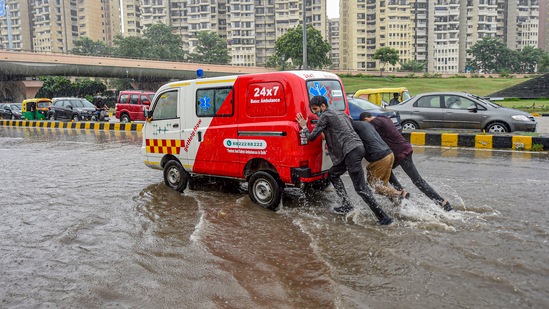 Men push an ambulance on a waterlogged road after heavy rains, near AIIMS Hospital in New Delhi.(PTI)
