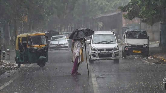 A man with an umbrella crosses the road amid heavy rain in New Delh on August 31.(PTI)