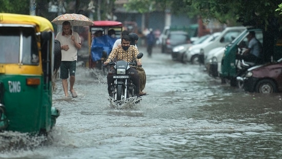 People wade through a waterlogged stretch near Mandawali in New Delhi on August 31.(HT Photo/Raj K Raj)