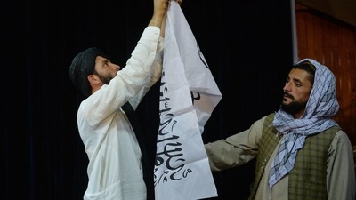 Men adjust the Taliban flag in Kabul ahead of a press conference. (AFP)