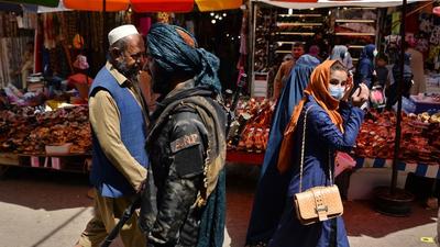 A Taliban fighter (centre) walks past shoppers along Mandawi market in Kabul, Afghanistan on Wednesday. (AFP) A Taliban fighter (centre) walks past shoppers along Mandawi market in Kabul, Afghanistan on Wednesday. (AFP)
