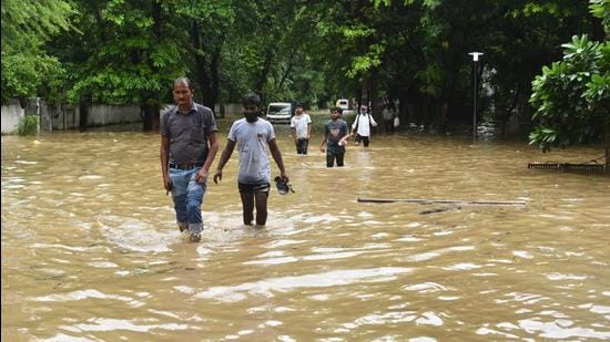 Pedestrians wade their way around near Galleria Market as heavy rainfall left the road waterlogged. (Vipin Kumar/HT PHOTO)