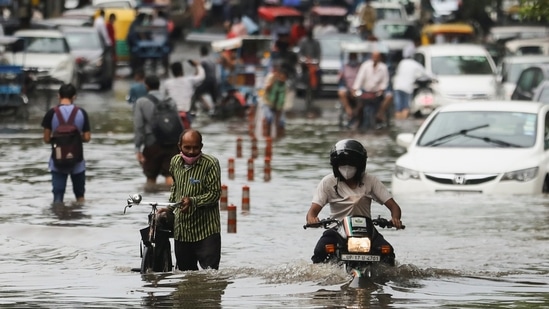 Men wade through a waterlogged street after heavy rains lashed Delhi and its neighbouring cities, including Gurgaon and Noida on September 1.(REUTERS)